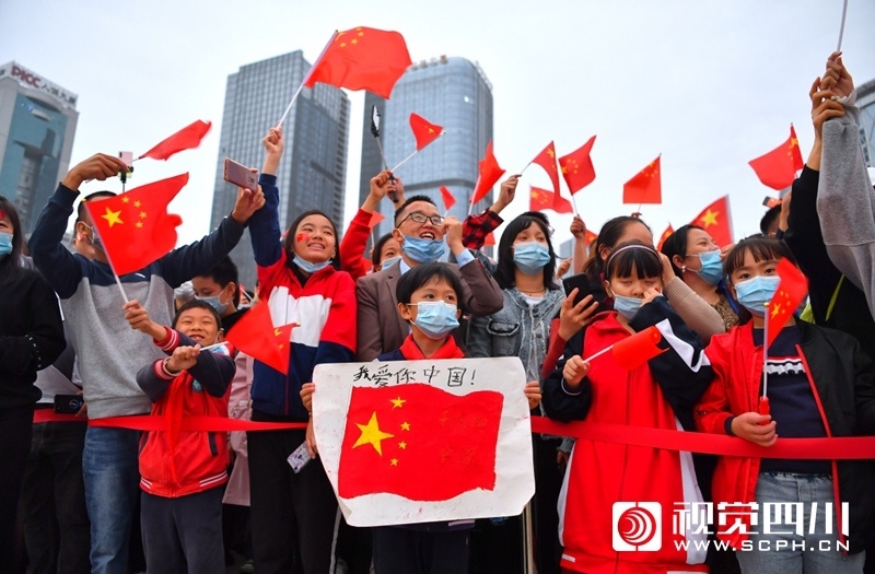许多市民手拿国旗自发到成都市天府广场与飘扬在广场上的五星红旗合影