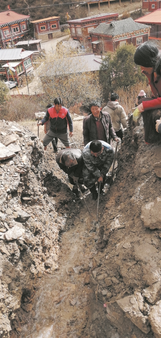 大家用钢钎将排水沟内的大石头撬走
