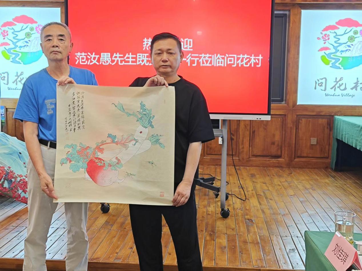 图片说明：著名画家、张大千外孙范汝愚（左）向问花村董事长杨仁祥赠送作品